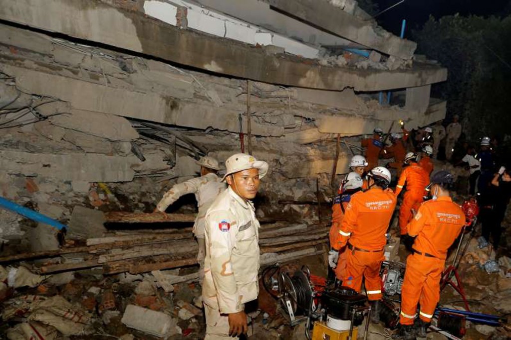 A rescue team searches for trapped workers at a collapsed building, which was under construction in Kep, Cambodia