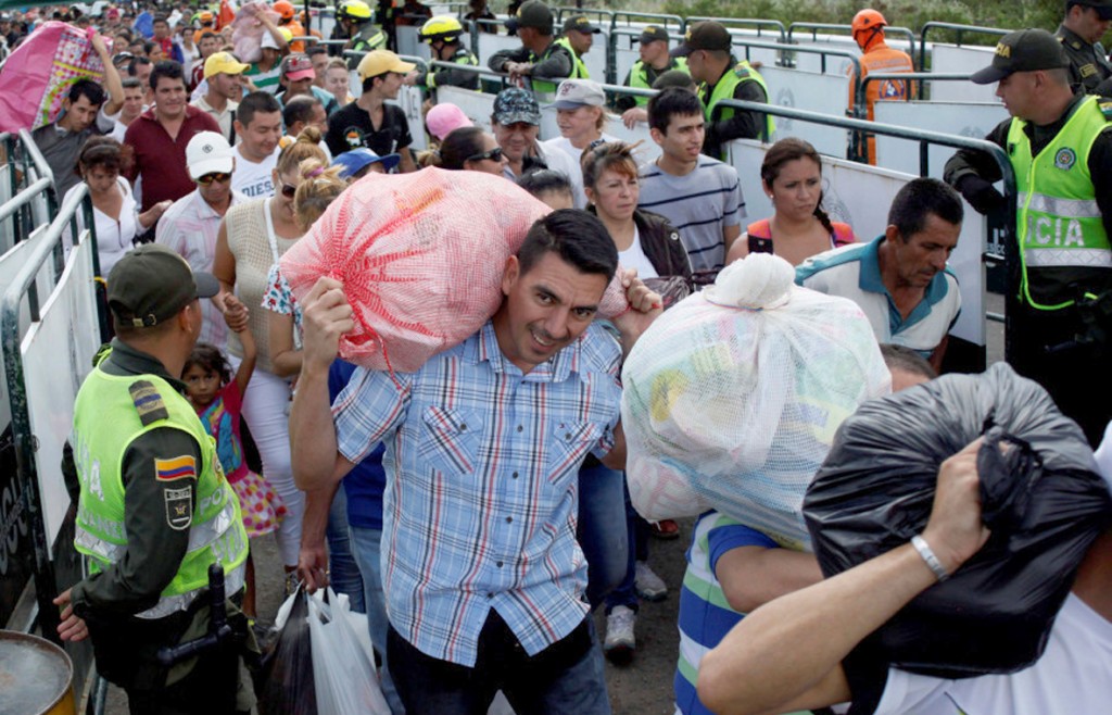 People are seen carrying bags and packages as they cross the Colombian-Venezuelan border over the Simon Bolivar international bridge after shopping in Cucuta, Colombia