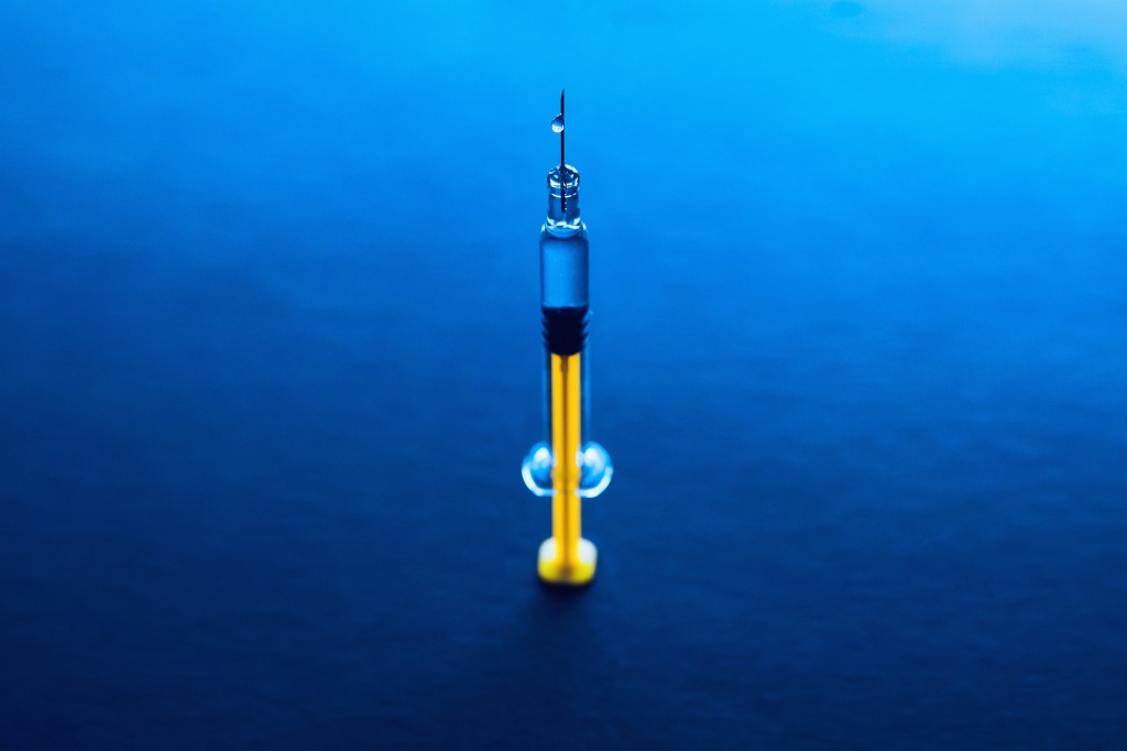 Yellow glass medical syringe over dark background